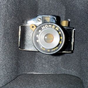 This object is a Homer subminiature camera, a vintage device produced in Japan